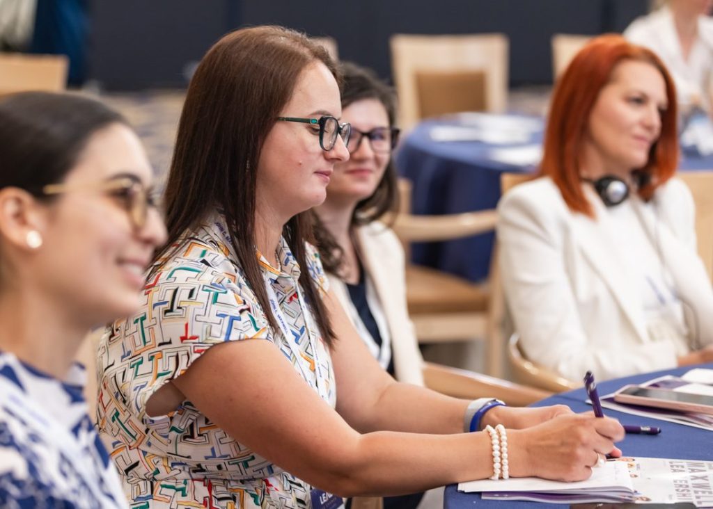 Participantă care își notează gândurile într-un caiet la un eveniment Maxwell Leadership România
